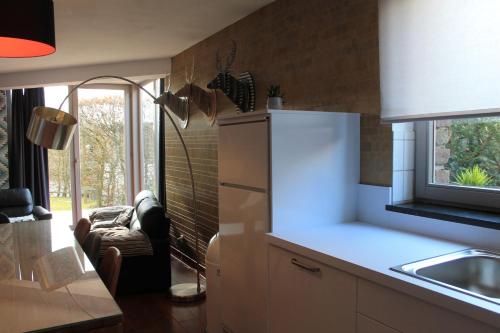 a kitchen with a refrigerator and a couch in it at Gite-ardennes & wellness - Ovifat - Coquelicots 7 pers in Ovifat
