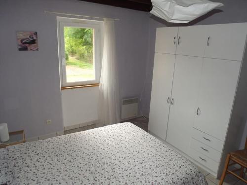 a white bedroom with a bed and a window at Gîte Tucolet in Hinx