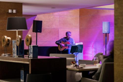 a man playing a guitar in a purple room at Hotel Marina Atlântico in Ponta Delgada