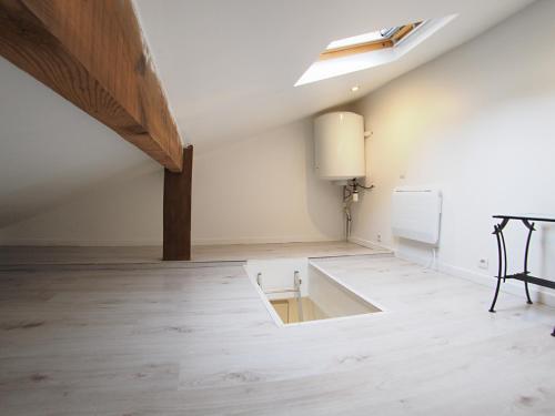 an attic room with a white ceiling and a table at Cosy Cottage in Vitry-sur-Seine