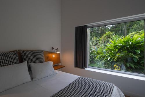 a bedroom with a bed and a large window at Sete Cidades Lake Lodge in Sete Cidades