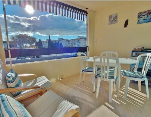 une pièce avec une table, des chaises et une fenêtre dans l'établissement Agréable Studio Cabine - piscine - parking - proche Plage RICHELIEU, au Cap d'Agde