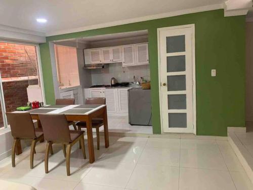 a kitchen with a table and chairs and a green wall at 306Hermoso, céntrico y acogedor loft en Cartagena in Cartagena de Indias