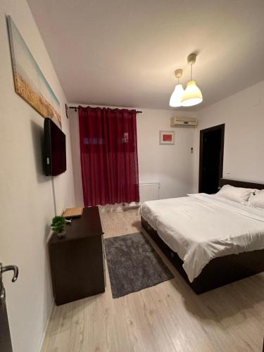 een slaapkamer met een bed en een rood gordijn bij Apartament Otopeni in Otopeni