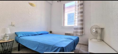 une chambre avec un lit bleu et une fenêtre dans l'établissement APPART f3 ,CLIM, PROCHE PLAGE, à Banyuls-sur-Mer