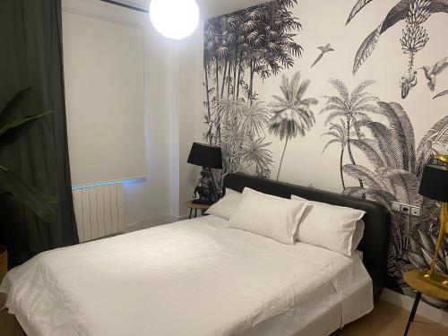 グラナダにあるAcogedor apartamento pleno centro de Granada y PARKINGのトロピカルな壁紙の白いベッドが備わるベッドルーム1室が備わります。