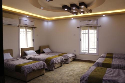 a room with four beds in a room with windows at Petra Mountain House in Wadi Musa