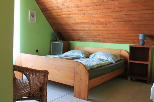 Ce lit se trouve dans un dortoir doté d'un plafond en bois. dans l'établissement Lenke Apartmanház, à Balatonlelle