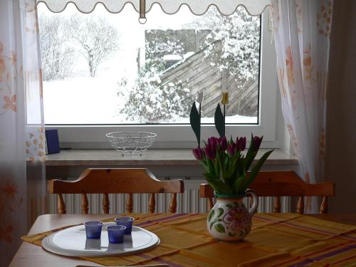 un tavolo da pranzo con vaso di fiori e finestra di Whg 4 - Ferien auf einem Resthof a Schönhagen