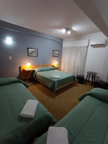 a bedroom with two green beds and a table at Hotel Iberia in Neuquén