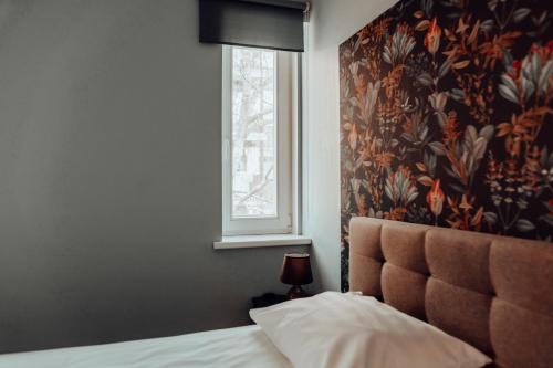 1 dormitorio con 1 cama con ventana y pared de flores en Central 1-bedroom Apartment with Bath & Balcony, en Tallin