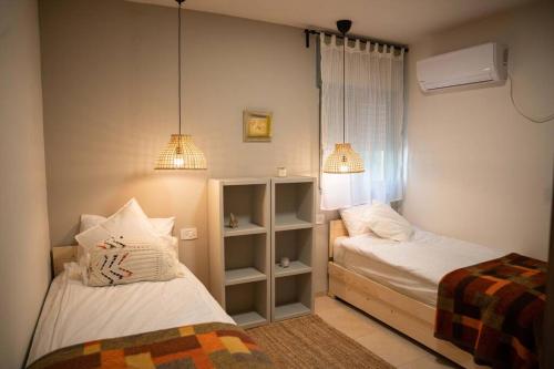 a small bedroom with two beds and two lamps at Brand New Zippi`s- karmiel in Karmiel
