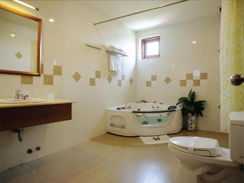 a bathroom with a tub and a toilet and a sink at Hoang Yen Hotel in Thuan An