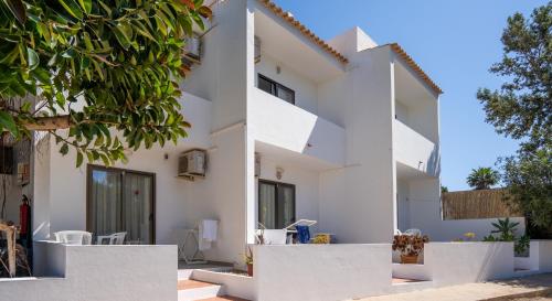 Casa blanca con paredes y árboles blancos en Apartamentos Playamar - Formentera Break, en Playa de Migjorn