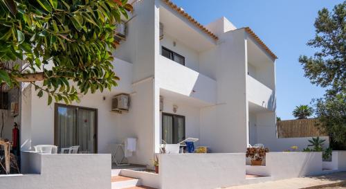 una casa blanca con paredes blancas y árboles en Apartamentos Playamar - Formentera Break, en Playa de Migjorn