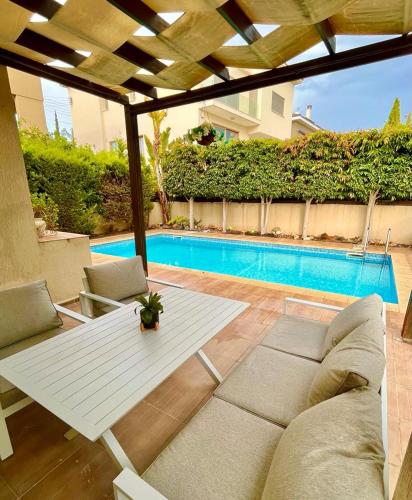 a patio with a white table and chairs and a pool at El Soleo Luxury Villa in Limassol
