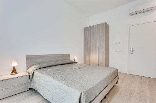 a white bedroom with a large bed and a door at Hotel Anversa Rimini in Rimini