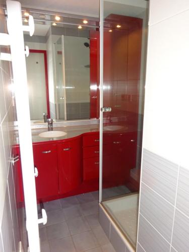 a bathroom with red cabinets and a glass shower at BIENVENUE AU LIORAN in Le Lioran