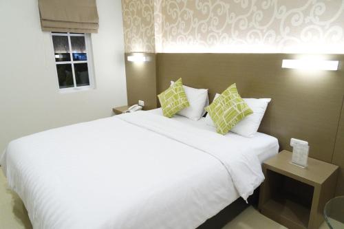a bedroom with a large white bed with two pillows at Yokotel Hotel in Bandung