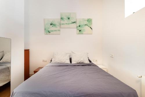 a bed in a bedroom with three paintings on the wall at Double room with private bathroom and private kitchen in Barcelona