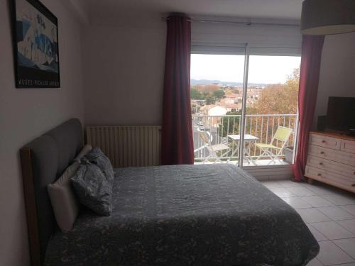 a bedroom with a bed and a view of a balcony at Residence d'Anjou - Grand studio avec balcon et parking privatif in Perpignan