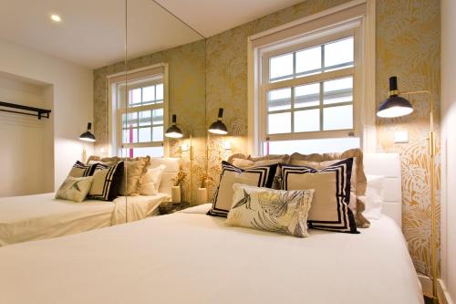 a bedroom with two beds and two windows at São Bento Golden Flat in Porto