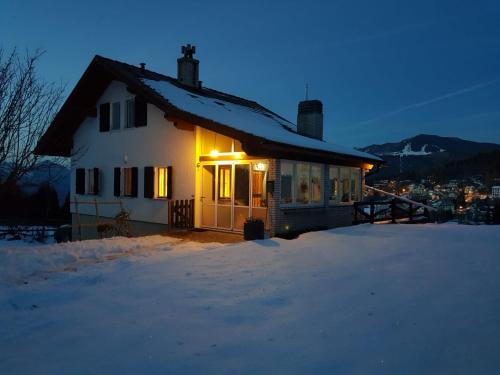 Una casa en la nieve con luces encendidas. en Chalet Heidi, en Serrada
