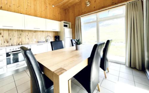 a kitchen with a wooden table and black chairs at Hidden Cottages in Kvíabekkur