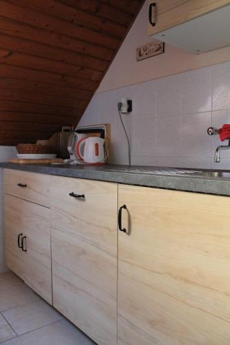 a kitchen with wooden cabinets and a counter top at Lenke Apartmanház in Balatonlelle