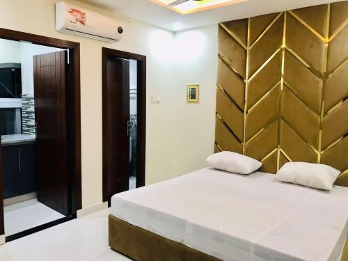 a bedroom with a bed with a gold headboard at Premier Heights Jhelum in Jhelum