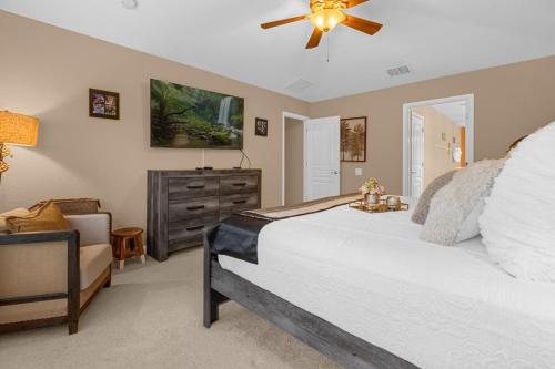 - une chambre avec un lit, un ventilateur de plafond et une chaise dans l'établissement Windsor Hills Villa w pool near Disney, à Coffeyville