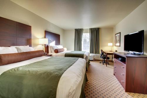 a hotel room with two beds and a flat screen tv at Cobblestone Inn & Suites Cambridge in Cambridge