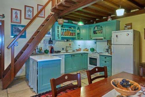 una cocina con armarios verdes, una mesa y una escalera en Thesspelia House, en Tsagkarada