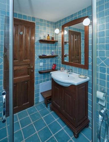 a blue tiled bathroom with a sink and a mirror at Thesspelia House in Tsagarada