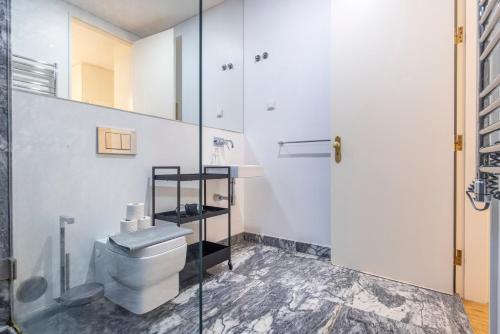 La salle de bains est pourvue de toilettes et d'une douche en verre. dans l'établissement Castelo Design Aparment W/ Balcony & Super View by LovelyStay, à Lisbonne