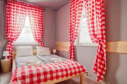 sypialnia z czerwono-białymi zasłonami szachowymi i łóżkiem w obiekcie Apartamenty Koniaków Residence w mieście Koniaków
