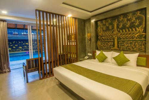 1 dormitorio con 1 cama con una pintura en la pared en Chhay Long Angkor Boutique Hotel Siem Reap, en Siem Reap