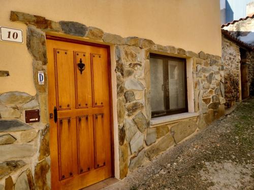 a stone building with a wooden door and a window at Casa rural Las Peñas in Saucelle