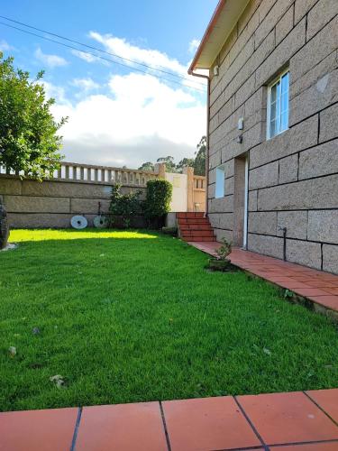 a yard with green grass next to a building at CarreraHouses OCouto in Pontevedra
