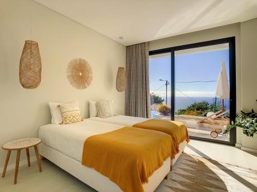 ein Schlafzimmer mit einem großen Bett und einem großen Fenster in der Unterkunft Noah - Private Sunset Hideaway by LovelyStay in Arco da Calheta