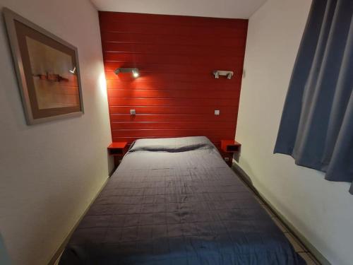 a bed in a room with a red wall at Bulle enchantée entre lac et montagne in Allevard