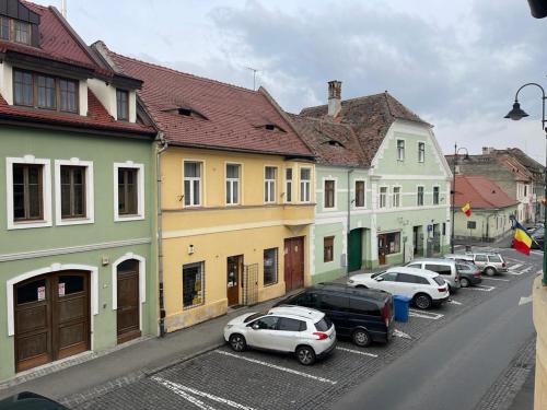 Una fila de coches aparcados en un estacionamiento al lado de edificios. en Family Residence, en Sibiu