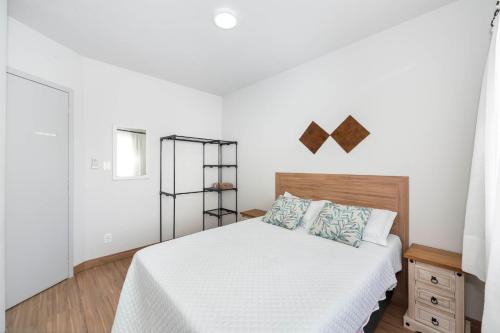 1 dormitorio con 1 cama con sábanas blancas y almohadas azules en DOÑA ALZIRA, en Bombinhas