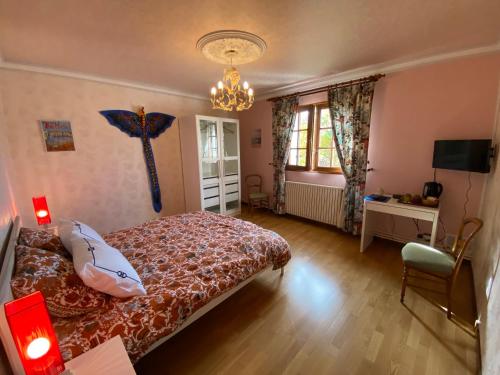 1 dormitorio con cama y lámpara de araña en La pommeraie76 en Saint-Ouen-sous-Bailly
