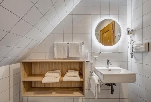 a white bathroom with a sink and a mirror at Hotel Schleuse in Munich