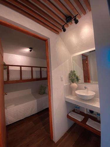 baño con lavabo, espejo y cama en Hotel Maya Jade, en Monterrico