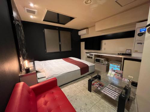 una camera con un letto e un divano rosso di 旭川ホテル818-大人専用 a Asahikawa