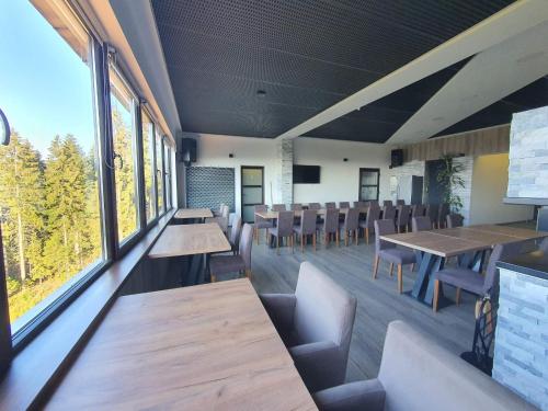 ein Restaurant mit Holztischen, Stühlen und Fenstern in der Unterkunft Planinska Kraljica in Gornje Pale