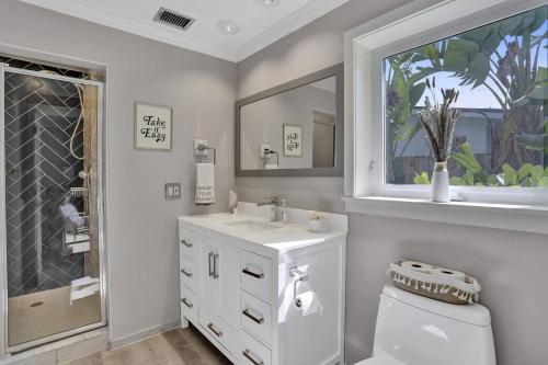 ein weißes Badezimmer mit einem Waschbecken und einem Spiegel in der Unterkunft Brand New! Heated Pool, Golf Cart, Next to Beach in Fort Lauderdale