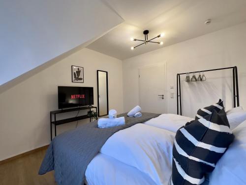 a bedroom with two white beds and a flat screen tv at Moderne Wohnung mit Küche & Parkplatz Ausblick auf den bayerischen Wald in Stephansposching